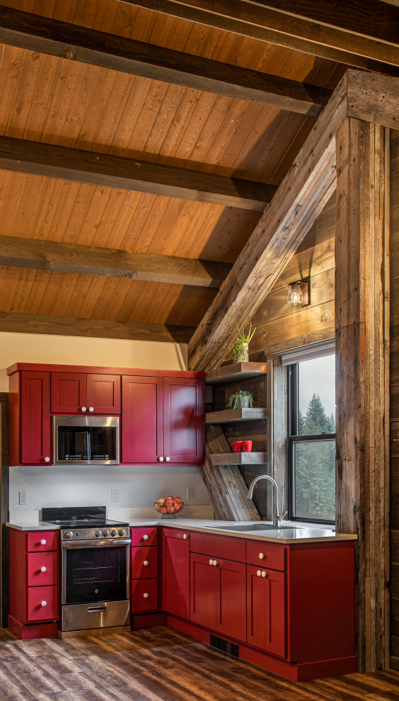 Design ideas for a small rustic l-shaped kitchen/diner in Seattle with a built-in sink, shaker cabinets, red cabinets, engineered stone countertops, white splashback, engineered quartz splashback, stainless steel appliances, medium hardwood flooring, an island and white worktops.