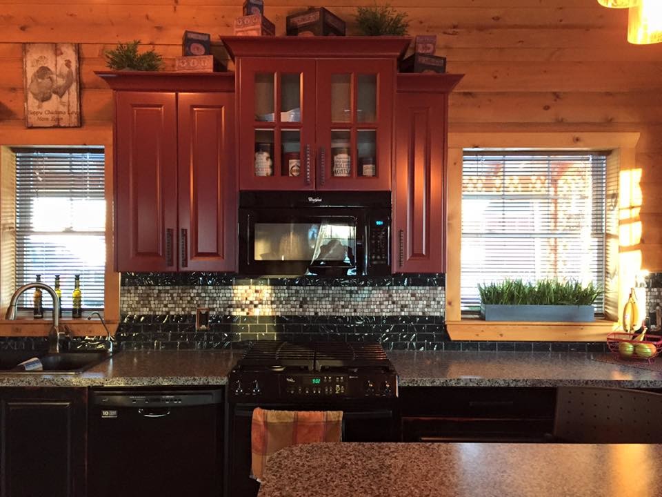 На фото: угловая кухня среднего размера в стиле кантри с накладной мойкой, фасадами с выступающей филенкой, красными фасадами, черной техникой и островом с