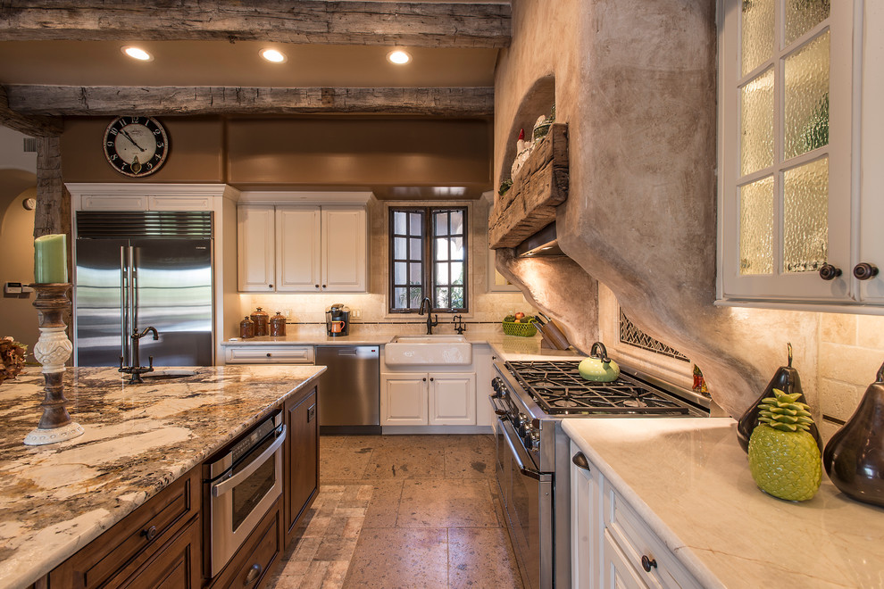Eat-in kitchen - huge country l-shaped brick floor eat-in kitchen idea in Phoenix with a farmhouse sink, glass-front cabinets, white cabinets, granite countertops, beige backsplash, stone tile backsplash, stainless steel appliances and an island