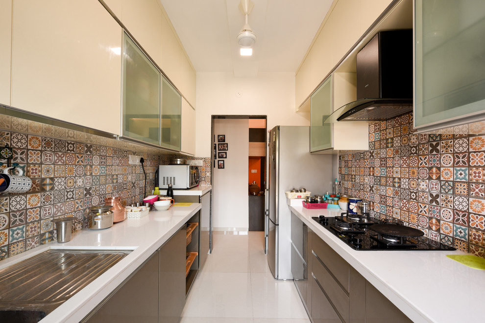 Cette photo montre une cuisine parallèle asiatique avec un évier encastré, un placard à porte plane, des portes de placard grises, une crédence multicolore, un électroménager en acier inoxydable, un sol blanc et un plan de travail blanc.