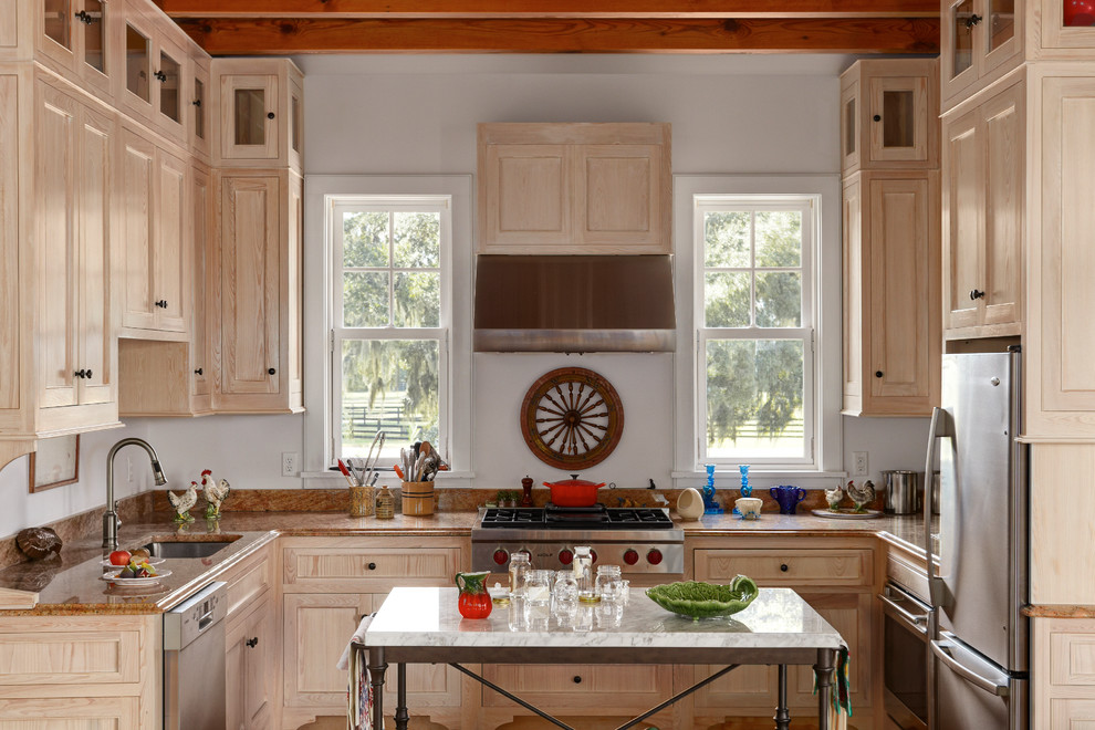 Aménagement d'une cuisine classique en U et bois clair avec un électroménager en acier inoxydable et un placard avec porte à panneau encastré.