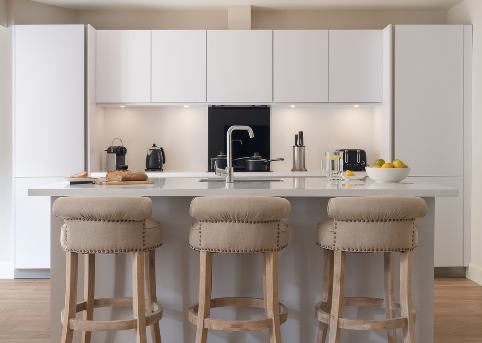 Moderne Küche mit Unterbauwaschbecken, flächenbündigen Schrankfronten, Küchenrückwand in Weiß, hellem Holzboden und Kücheninsel in Edinburgh