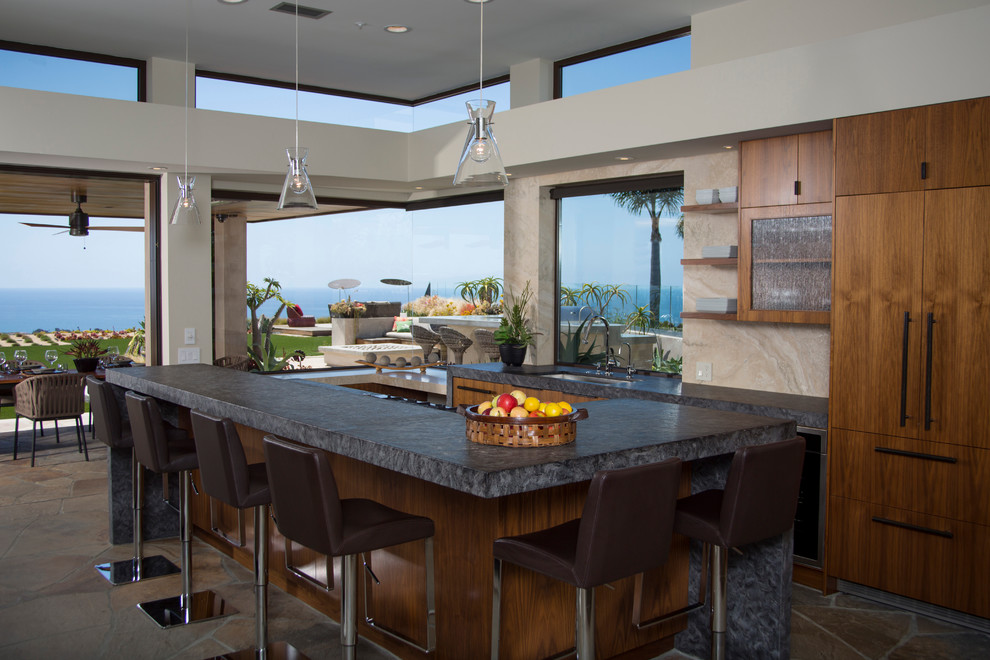 This is an example of a contemporary open plan kitchen in Orange County with a submerged sink, flat-panel cabinets, dark wood cabinets, beige splashback, integrated appliances and an island.
