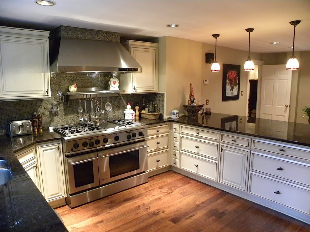 Elegant u-shaped medium tone wood floor eat-in kitchen photo in New York with a double-bowl sink, beaded inset cabinets, white cabinets, granite countertops, mosaic tile backsplash, stainless steel appliances, no island and multicolored backsplash