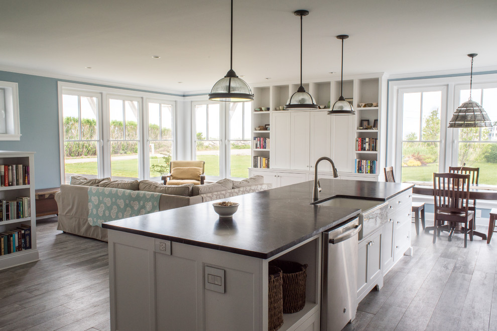 Transitional single-wall painted wood floor open concept kitchen photo in Manchester with a farmhouse sink, white cabinets, granite countertops, stainless steel appliances and an island