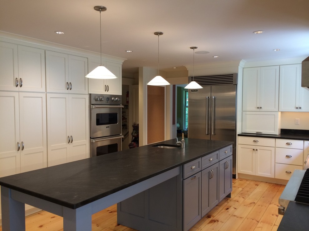 Inspiration for a large country u-shaped enclosed kitchen in Boston with a submerged sink, shaker cabinets, white cabinets, granite worktops, stainless steel appliances, light hardwood flooring, an island and white splashback.