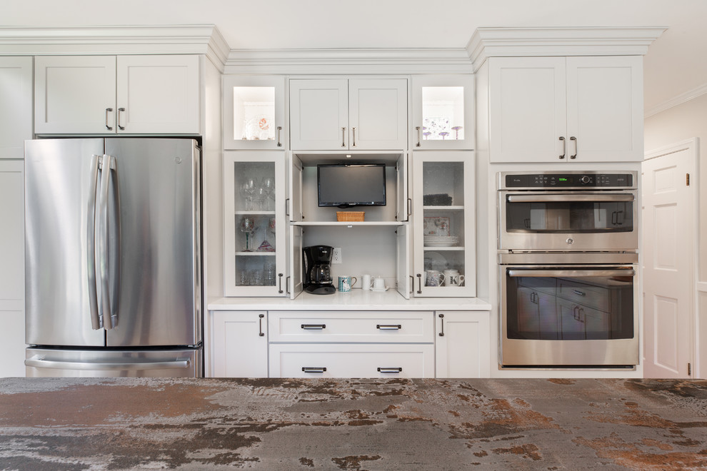 Exempel på ett avskilt, stort klassiskt vit vitt u-kök, med en enkel diskho, skåp i shakerstil, grå skåp, bänkskiva i kvarts, grått stänkskydd, rostfria vitvaror, mellanmörkt trägolv, en köksö och brunt golv