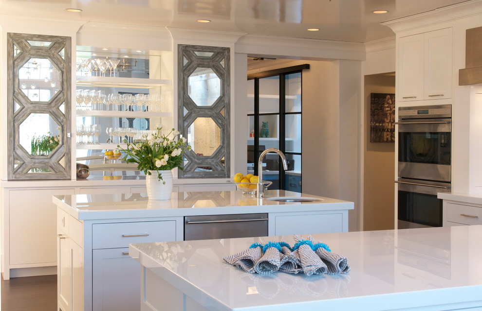 Diseño de cocina gris y blanca clásica renovada con fregadero bajoencimera, armarios con paneles empotrados, puertas de armario blancas y electrodomésticos de acero inoxidable