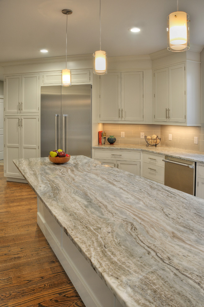 Exempel på ett stort modernt l-kök, med en undermonterad diskho, luckor med profilerade fronter, vita skåp, bänkskiva i kvartsit, grått stänkskydd, stänkskydd i glaskakel, rostfria vitvaror, mellanmörkt trägolv, en köksö och brunt golv
