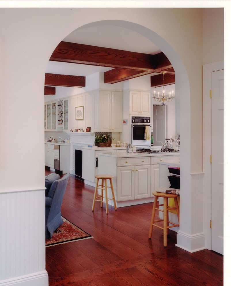 Große Klassische Wohnküche mit profilierten Schrankfronten, weißen Schränken, dunklem Holzboden und Kücheninsel in New York