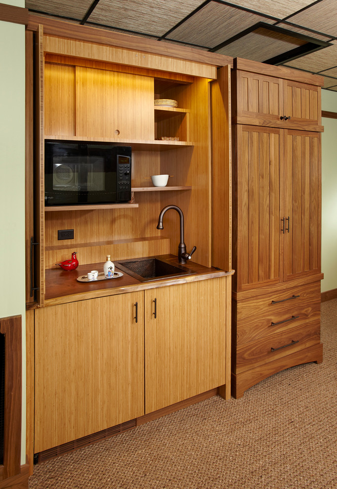 Example of a small asian single-wall carpeted kitchen design in Chicago with a drop-in sink, flat-panel cabinets, light wood cabinets, black appliances and no island