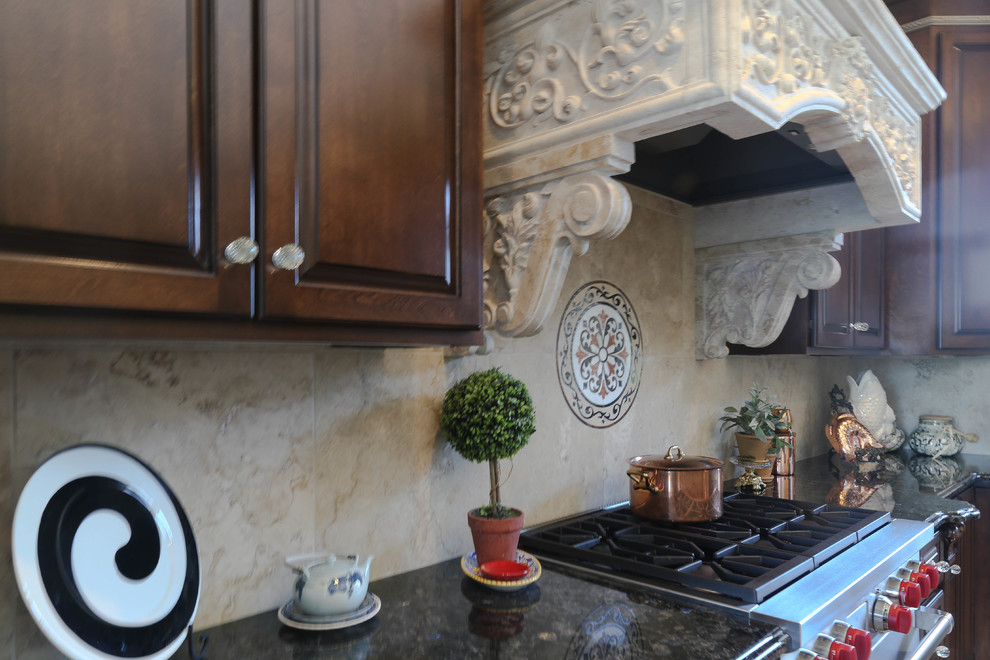Cette image montre une grande cuisine américaine méditerranéenne en L et bois foncé avec un évier encastré, un placard avec porte à panneau surélevé, un plan de travail en granite, une crédence beige, une crédence en carrelage de pierre, un électroménager en acier inoxydable, un sol en carrelage de porcelaine, 2 îlots et un sol beige.