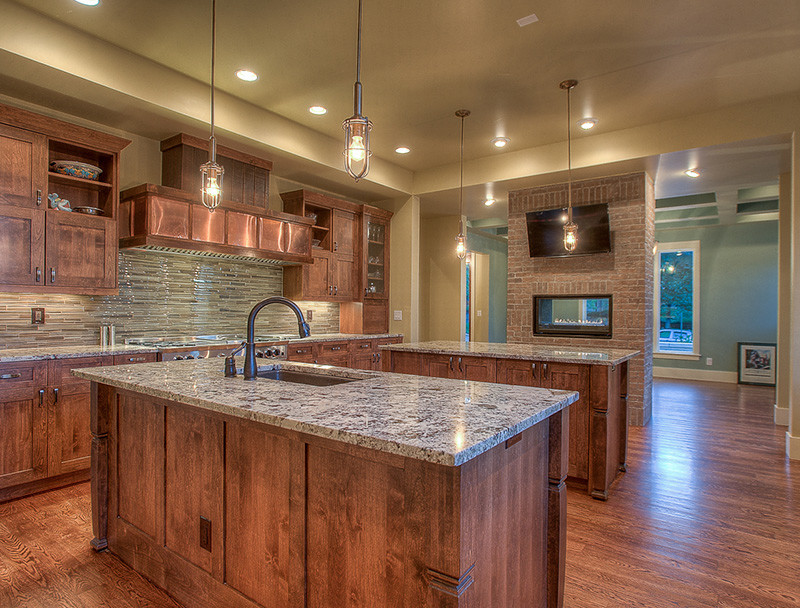 Mid-sized eclectic l-shaped medium tone wood floor and brown floor enclosed kitchen photo in Denver with an undermount sink, shaker cabinets, medium tone wood cabinets, granite countertops, beige backsplash, glass tile backsplash, stainless steel appliances and two islands