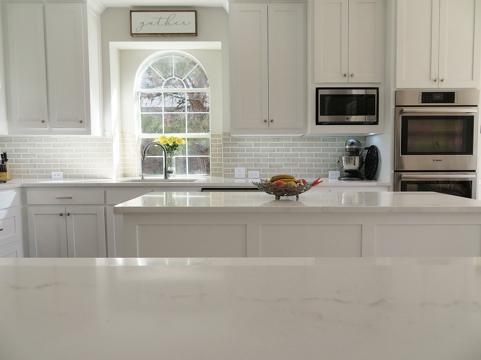 Exempel på ett vit vitt kök, med en enkel diskho, skåp i shakerstil, vita skåp, bänkskiva i kvarts, beige stänkskydd, stänkskydd i keramik, rostfria vitvaror, mörkt trägolv, en köksö och brunt golv
