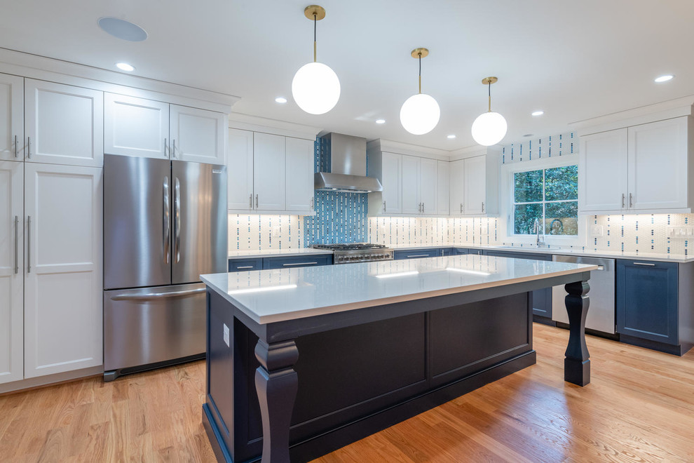 Inspiration for a mid-sized l-shaped medium tone wood floor and brown floor open concept kitchen remodel in Other with an undermount sink, shaker cabinets, white cabinets, multicolored backsplash, stainless steel appliances, an island and white countertops