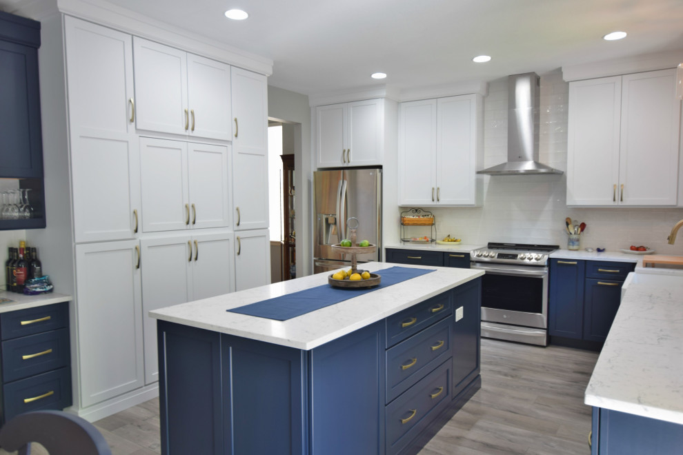 Eat-in kitchen - large transitional u-shaped eat-in kitchen idea in Denver with a farmhouse sink, shaker cabinets, white cabinets, quartz countertops, white backsplash, glass tile backsplash, stainless steel appliances and an island