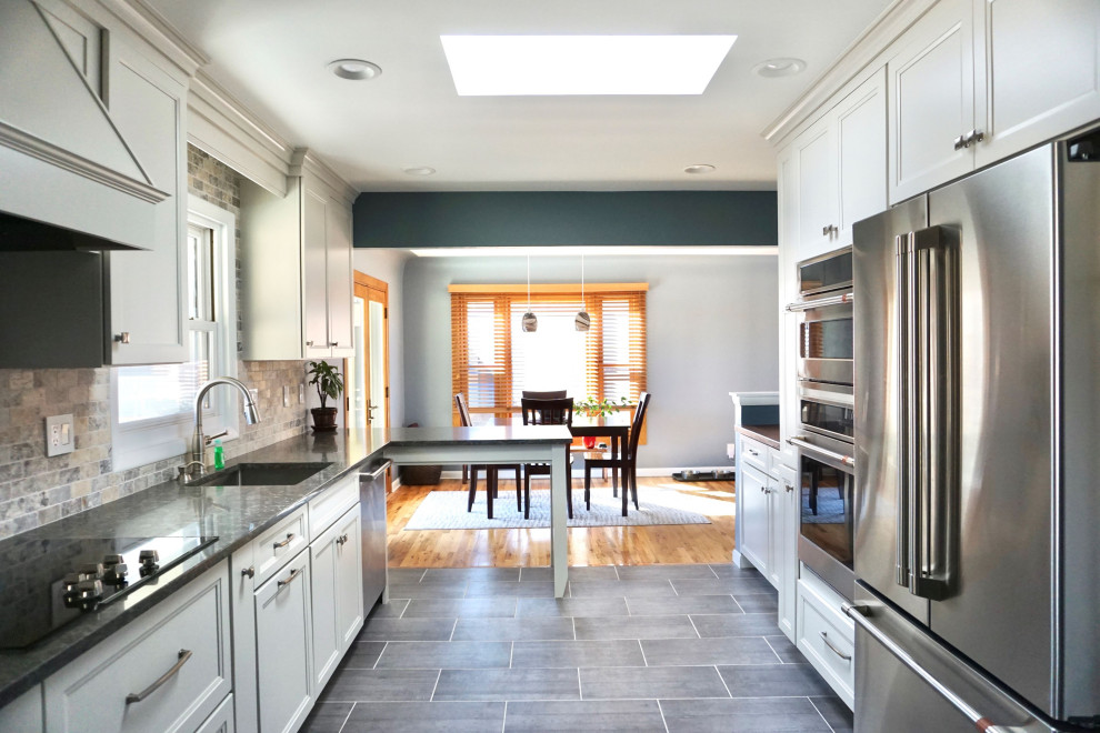 Klassisk inredning av ett mellanstort grå grått kök, med en undermonterad diskho, skåp i shakerstil, vita skåp, bänkskiva i kvarts, beige stänkskydd, rostfria vitvaror och en halv köksö