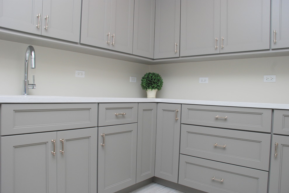 This is an example of a large traditional l-shaped kitchen pantry in Chicago with an integrated sink, flat-panel cabinets, grey cabinets, composite countertops, ceramic flooring and no island.