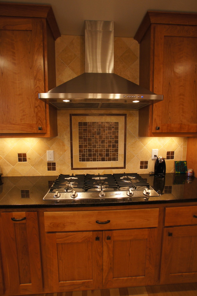 Foto på ett amerikanskt kök, med en undermonterad diskho, skåp i shakerstil, skåp i mellenmörkt trä, granitbänkskiva, beige stänkskydd, stänkskydd i stenkakel och rostfria vitvaror