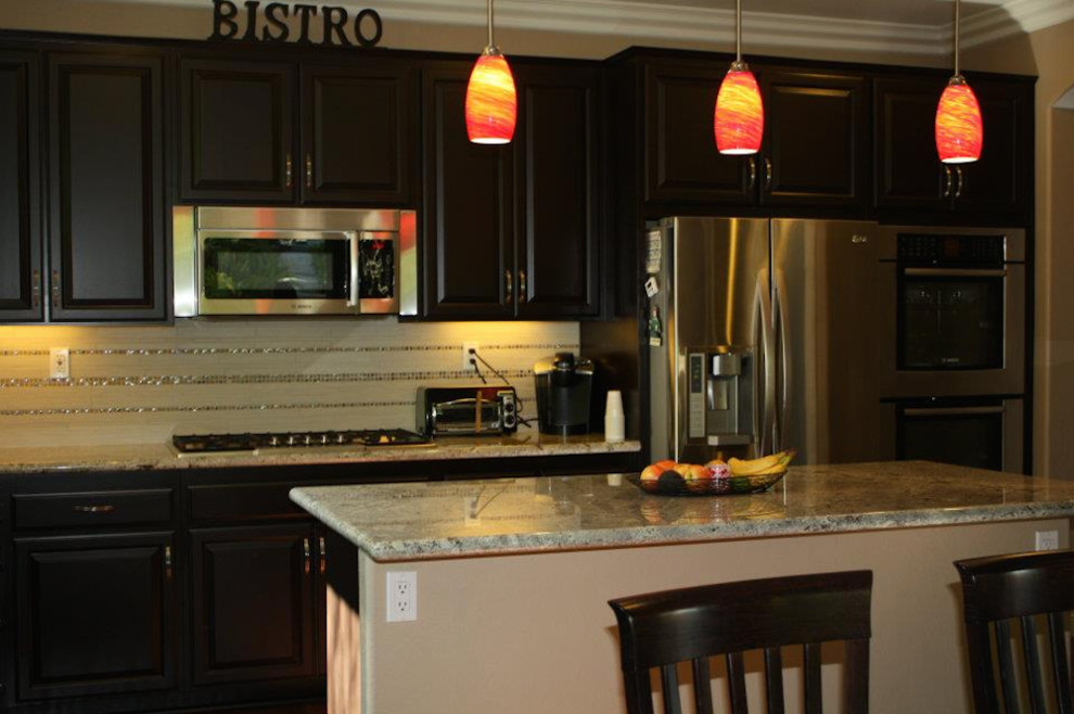 Foto på ett mellanstort vintage flerfärgad kök, med en undermonterad diskho, luckor med upphöjd panel, skåp i mörkt trä, granitbänkskiva, flerfärgad stänkskydd, stänkskydd i mosaik, rostfria vitvaror, mellanmörkt trägolv, en köksö och brunt golv