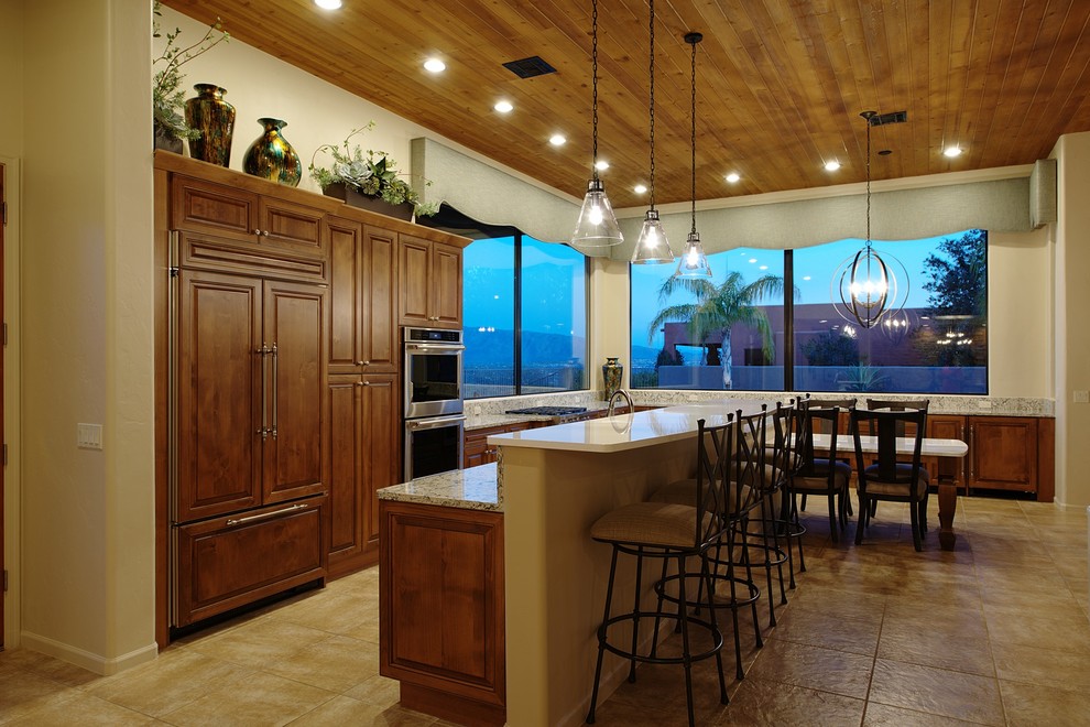 Design ideas for a large traditional l-shaped kitchen/diner in Phoenix with a submerged sink, raised-panel cabinets, brown cabinets, engineered stone countertops, multi-coloured splashback, integrated appliances, porcelain flooring, an island and beige floors.