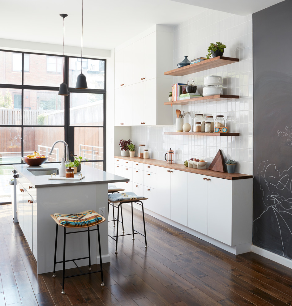 Zweizeilige Moderne Küche mit Unterbauwaschbecken, flächenbündigen Schrankfronten, weißen Schränken, Arbeitsplatte aus Holz, Küchenrückwand in Weiß, dunklem Holzboden, Kücheninsel, braunem Boden und brauner Arbeitsplatte in New York