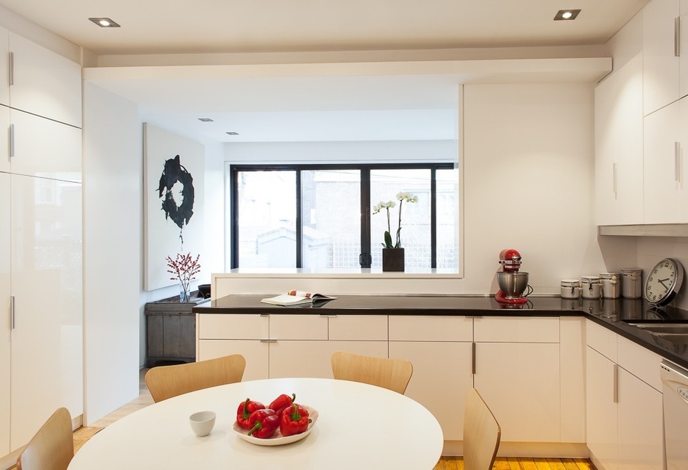 На фото: кухня в современном стиле с обеденным столом, плоскими фасадами и белыми фасадами с