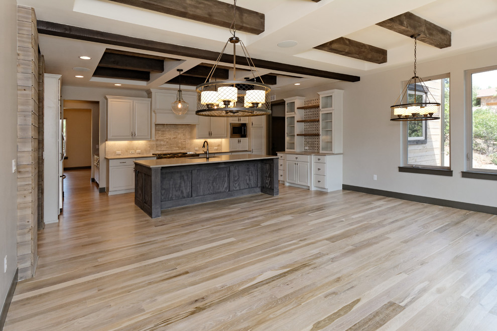 Eat-in kitchen - large rustic u-shaped light wood floor eat-in kitchen idea in Minneapolis with an undermount sink, raised-panel cabinets, white cabinets, quartz countertops, beige backsplash, stone slab backsplash, stainless steel appliances and an island