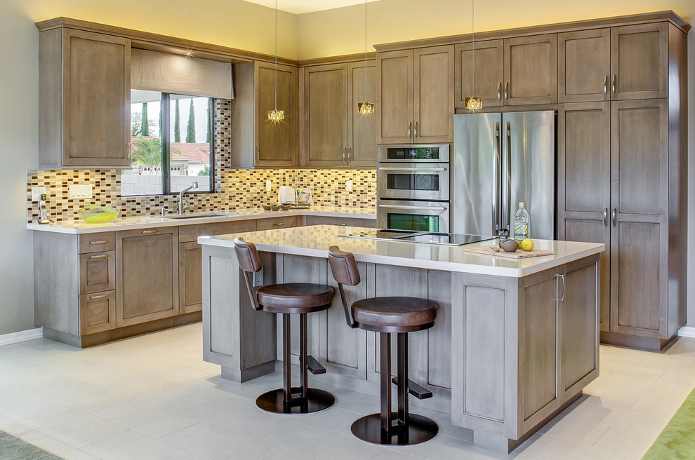This is an example of a traditional l-shaped kitchen in Phoenix with a submerged sink, shaker cabinets, light wood cabinets, multi-coloured splashback, stainless steel appliances, an island and white floors.