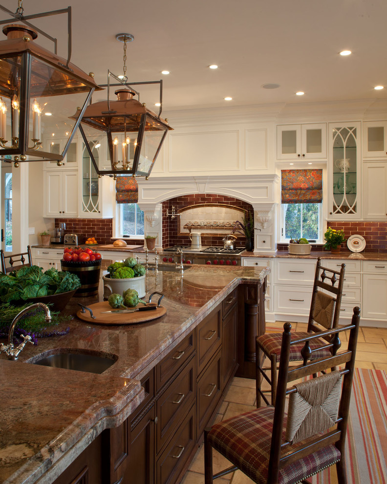 Foto på ett stort vintage kök, med granitbänkskiva, en undermonterad diskho, vita skåp, brunt stänkskydd, rostfria vitvaror och en köksö