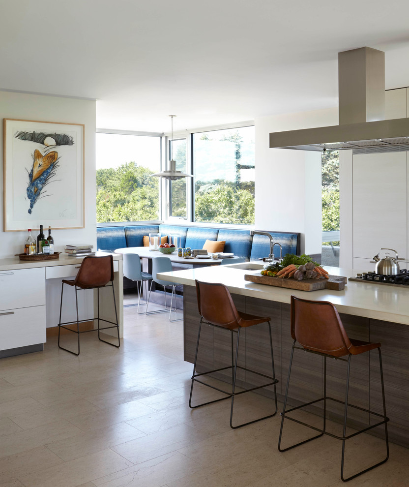 Cette image montre une grande cuisine américaine design avec îlot, un placard à porte plane, plan de travail en marbre, un électroménager en acier inoxydable et parquet clair.