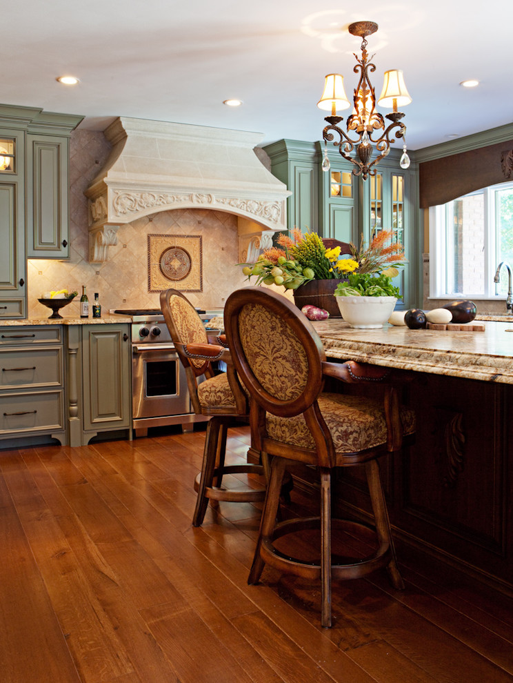 Exempel på ett stort klassiskt kök, med en undermonterad diskho, luckor med upphöjd panel, gröna skåp, granitbänkskiva, beige stänkskydd, stänkskydd i keramik, rostfria vitvaror, mellanmörkt trägolv och en köksö