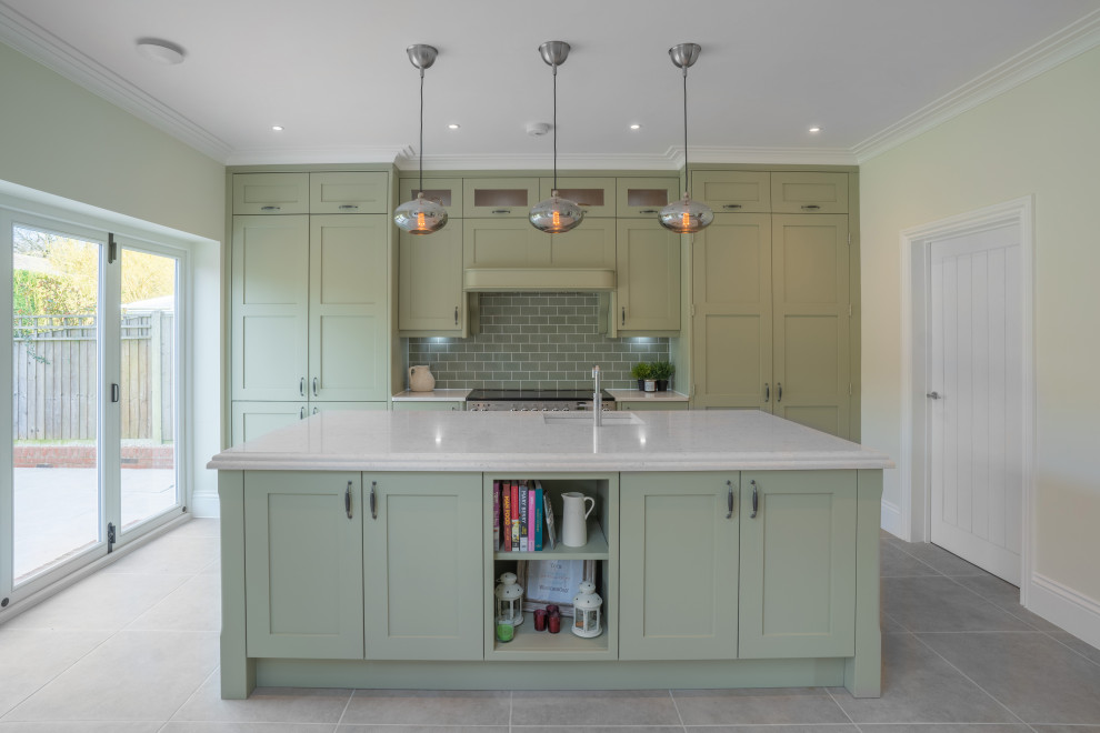 Classic galley kitchen in Essex with a submerged sink, shaker cabinets, green cabinets, grey splashback, mosaic tiled splashback, an island, grey floors and white worktops.