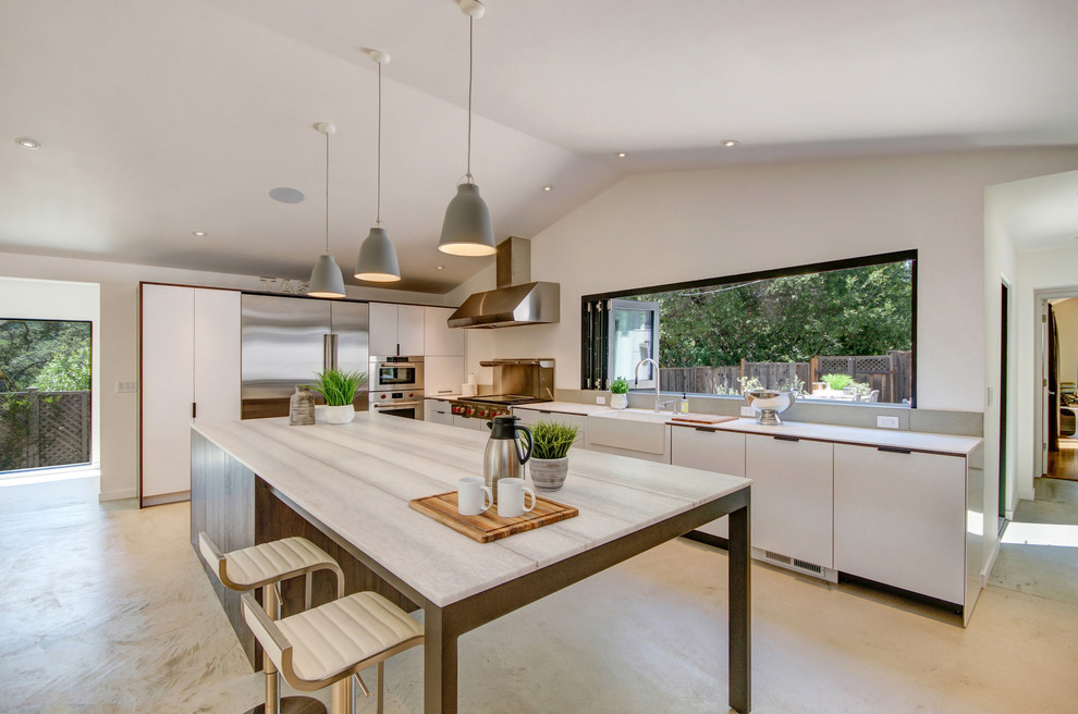 Eat-in kitchen - country l-shaped concrete floor and gray floor eat-in kitchen idea in San Francisco with a farmhouse sink, flat-panel cabinets, white cabinets, marble countertops, stainless steel appliances, an island and white countertops
