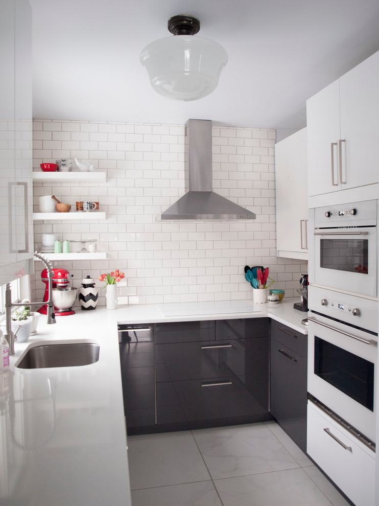 Geschlossene, Kleine Moderne Küche in U-Form mit Unterbauwaschbecken, flächenbündigen Schrankfronten, grauen Schränken, Küchenrückwand in Weiß, Rückwand aus Metrofliesen und weißen Elektrogeräten in Montreal