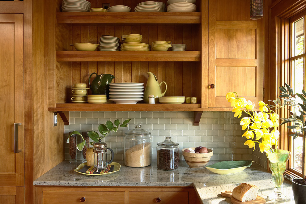 Foto på ett amerikanskt grå kök, med skåp i ljust trä, grönt stänkskydd, stänkskydd i tunnelbanekakel, luckor med infälld panel, granitbänkskiva och en halv köksö