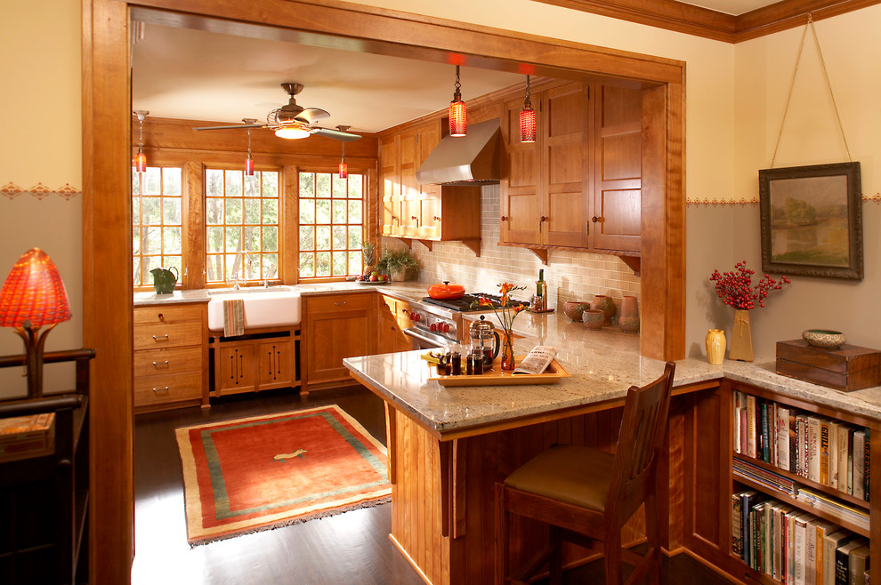 Bild på ett amerikanskt kök, med en rustik diskho, luckor med infälld panel, skåp i mellenmörkt trä, granitbänkskiva, stänkskydd i tunnelbanekakel, rostfria vitvaror, mörkt trägolv och en halv köksö