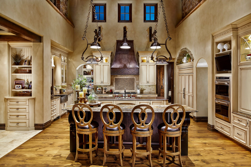 Foto de cocina mediterránea abierta con puertas de armario beige, electrodomésticos de acero inoxidable, suelo de madera en tonos medios y dos o más islas