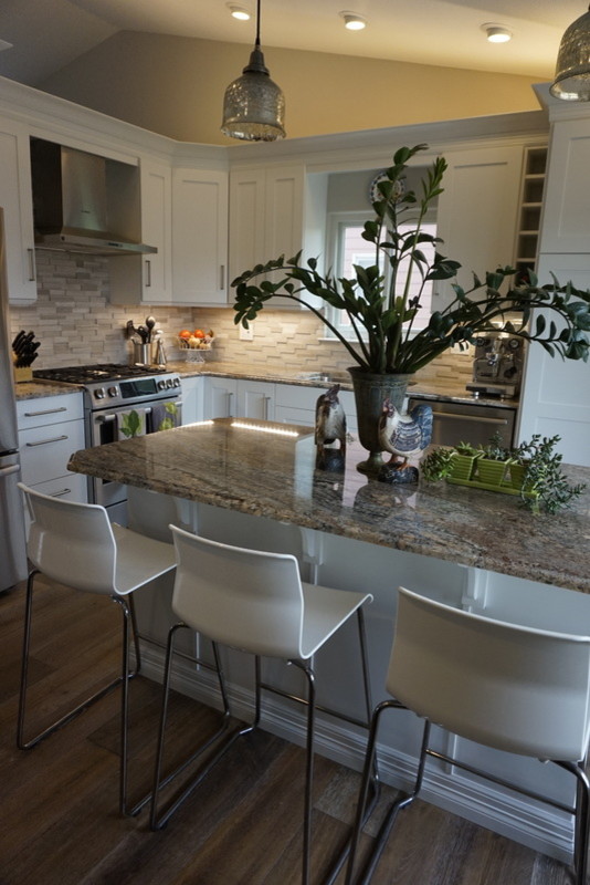 Eat-in kitchen - contemporary medium tone wood floor eat-in kitchen idea in Other with an undermount sink, shaker cabinets, white cabinets, granite countertops, gray backsplash, limestone backsplash, stainless steel appliances, an island and brown countertops