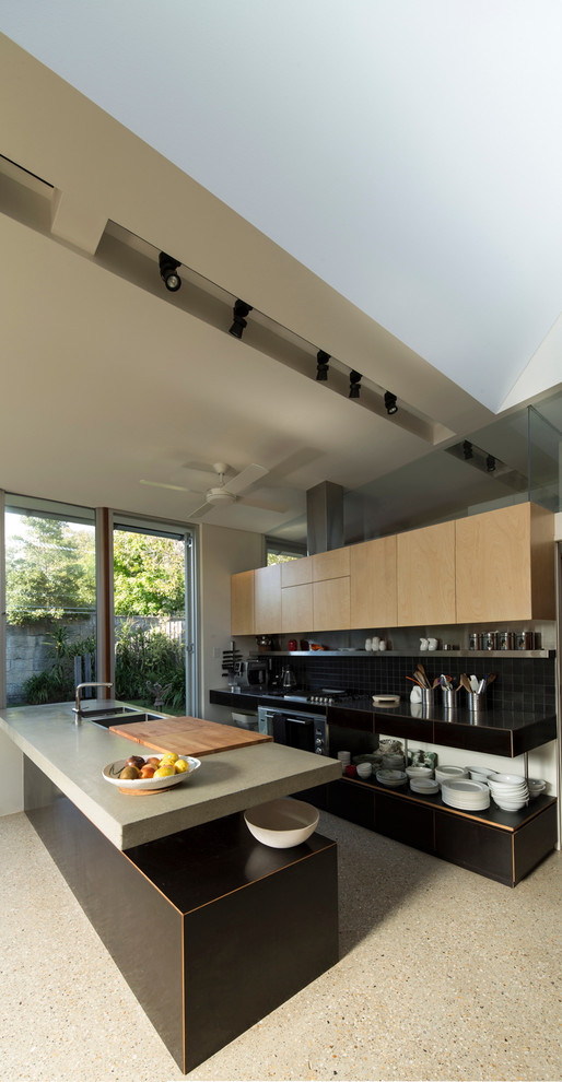 Foto de cocina contemporánea con fregadero encastrado, armarios con paneles lisos, encimera de cemento, salpicadero negro y suelo de cemento