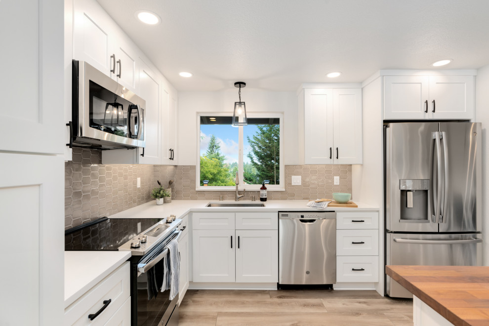 Bild på ett mellanstort funkis vit vitt kök, med en undermonterad diskho, skåp i shakerstil, vita skåp, bänkskiva i kvarts, grått stänkskydd, stänkskydd i keramik, rostfria vitvaror, vinylgolv, en köksö och grått golv