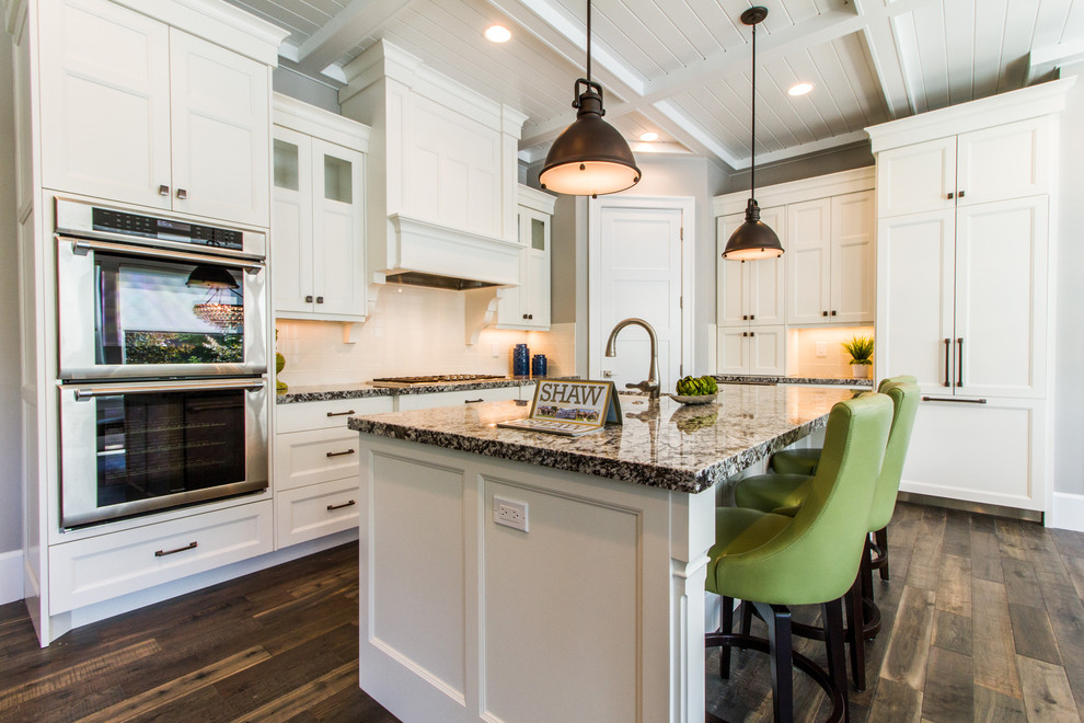 Photo of a large classic l-shaped open plan kitchen in Salt Lake City with shaker cabinets, white cabinets, granite worktops, an island, a submerged sink, integrated appliances and dark hardwood flooring.