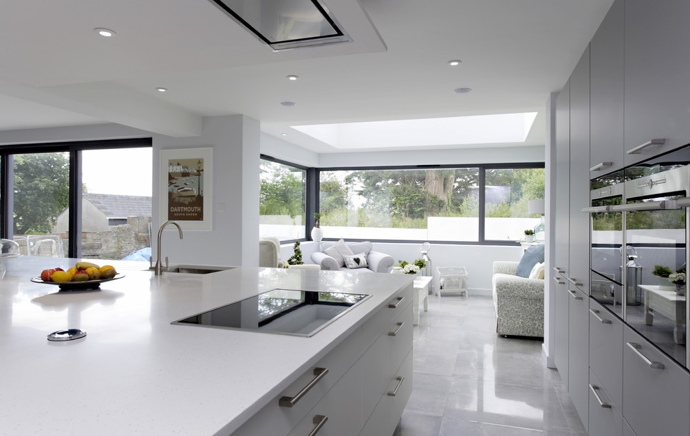 Exemple d'une cuisine moderne avec des portes de placard blanches, un électroménager en acier inoxydable, sol en stratifié, îlot et un sol gris.
