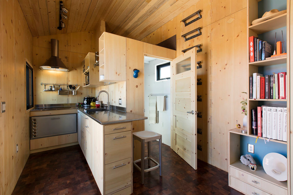 Idéer för ett litet modernt kök, med en undermonterad diskho, släta luckor, skåp i ljust trä, bänkskiva i rostfritt stål, beige stänkskydd, stänkskydd i trä, rostfria vitvaror, mörkt trägolv, en halv köksö och brunt golv