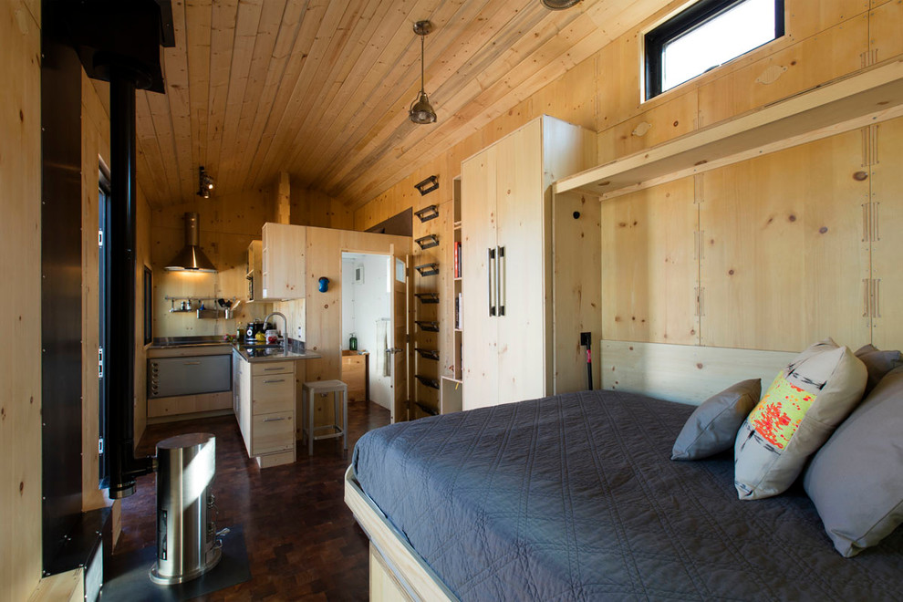 Bild på ett litet funkis kök, med en undermonterad diskho, släta luckor, skåp i ljust trä, bänkskiva i rostfritt stål, beige stänkskydd, stänkskydd i trä, rostfria vitvaror, mörkt trägolv, en halv köksö och brunt golv
