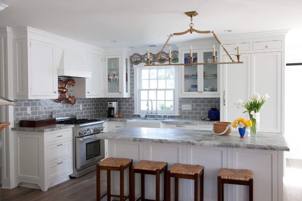 Maritime Küche in grau-weiß in L-Form mit Küchenrückwand in Grau, Landhausspüle, Schrankfronten im Shaker-Stil, weißen Schränken, Rückwand aus Metrofliesen, Elektrogeräten mit Frontblende und braunem Holzboden in San Diego