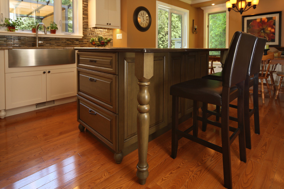 Klassisk inredning av ett mellanstort kök, med en rustik diskho, luckor med upphöjd panel, gröna skåp, bänkskiva i kvarts, flerfärgad stänkskydd, stänkskydd i stickkakel, rostfria vitvaror, mellanmörkt trägolv och en köksö