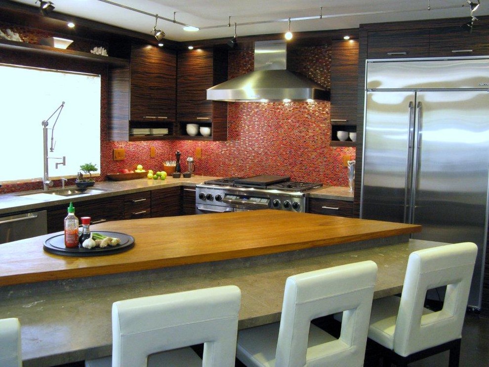 Exemple d'une grande cuisine américaine tendance en L et bois foncé avec un placard à porte plane, une crédence rouge, une crédence en mosaïque, un électroménager en acier inoxydable et îlot.