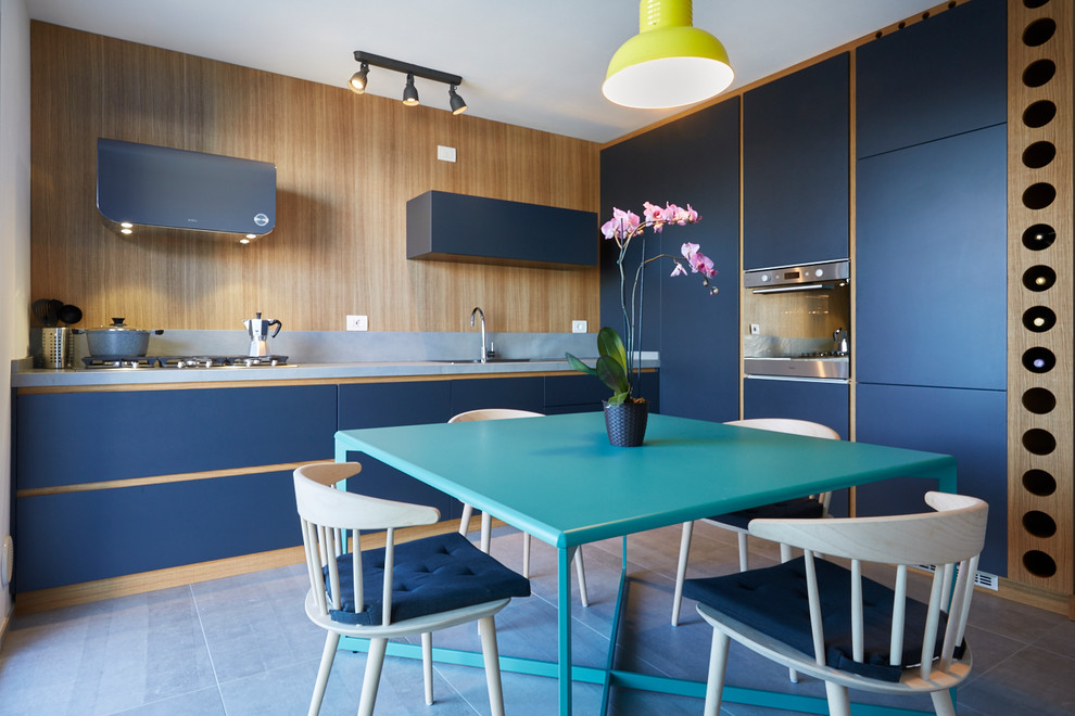 Immagine di una cucina lineare minimal chiusa con ante lisce, ante blu, elettrodomestici in acciaio inossidabile, nessuna isola e pavimento grigio