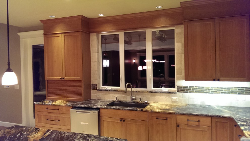 Example of an arts and crafts l-shaped eat-in kitchen design in Seattle with an undermount sink, recessed-panel cabinets, medium tone wood cabinets, granite countertops, beige backsplash, ceramic backsplash and stainless steel appliances